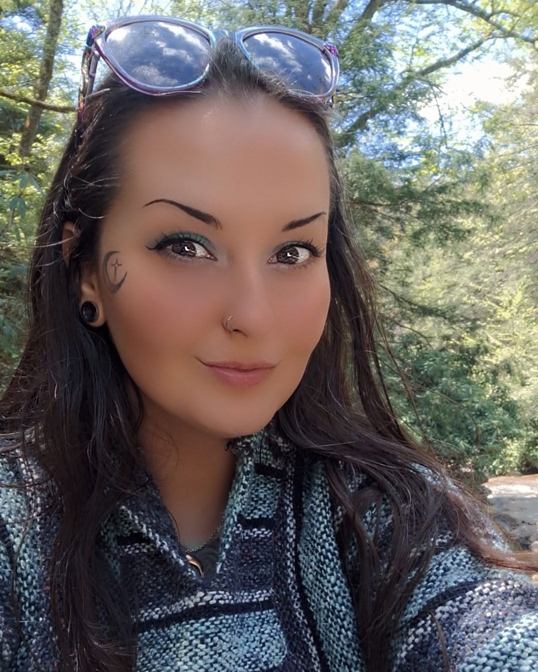 Jenna, the artist, smiling in the sunlight under the trees