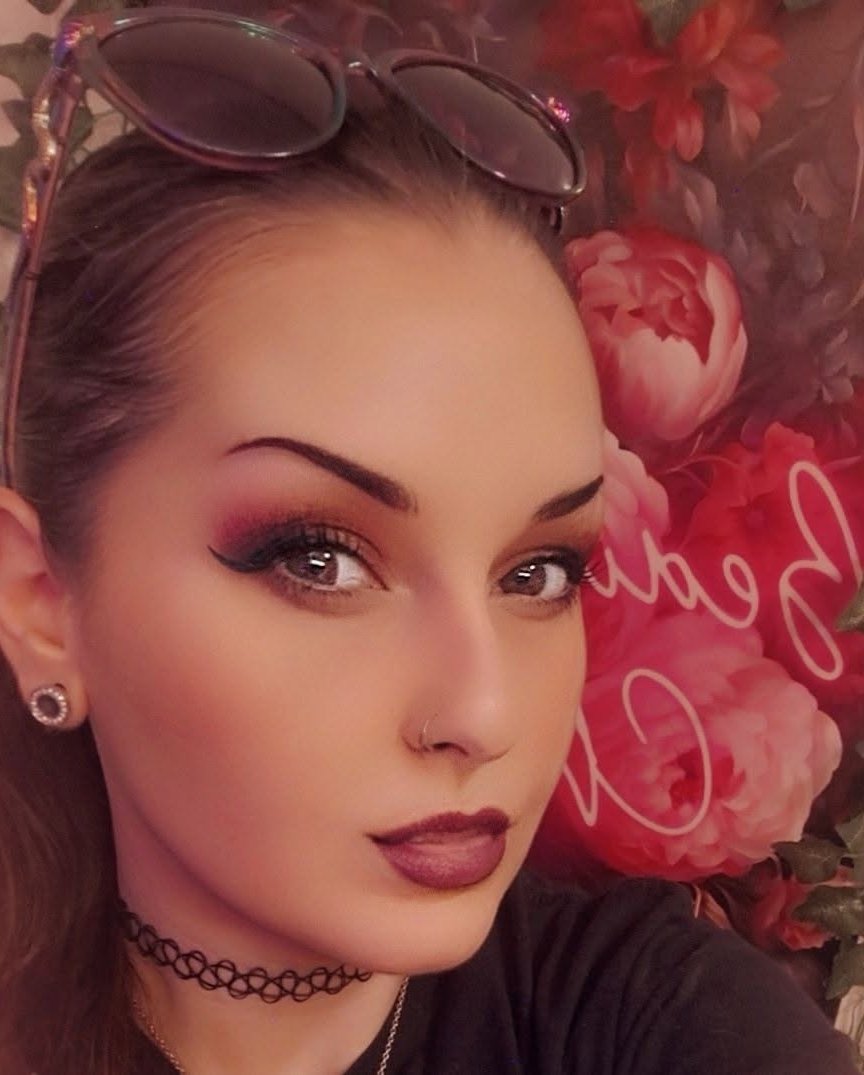 Jenna, the artist, in front of a wall of pink roses