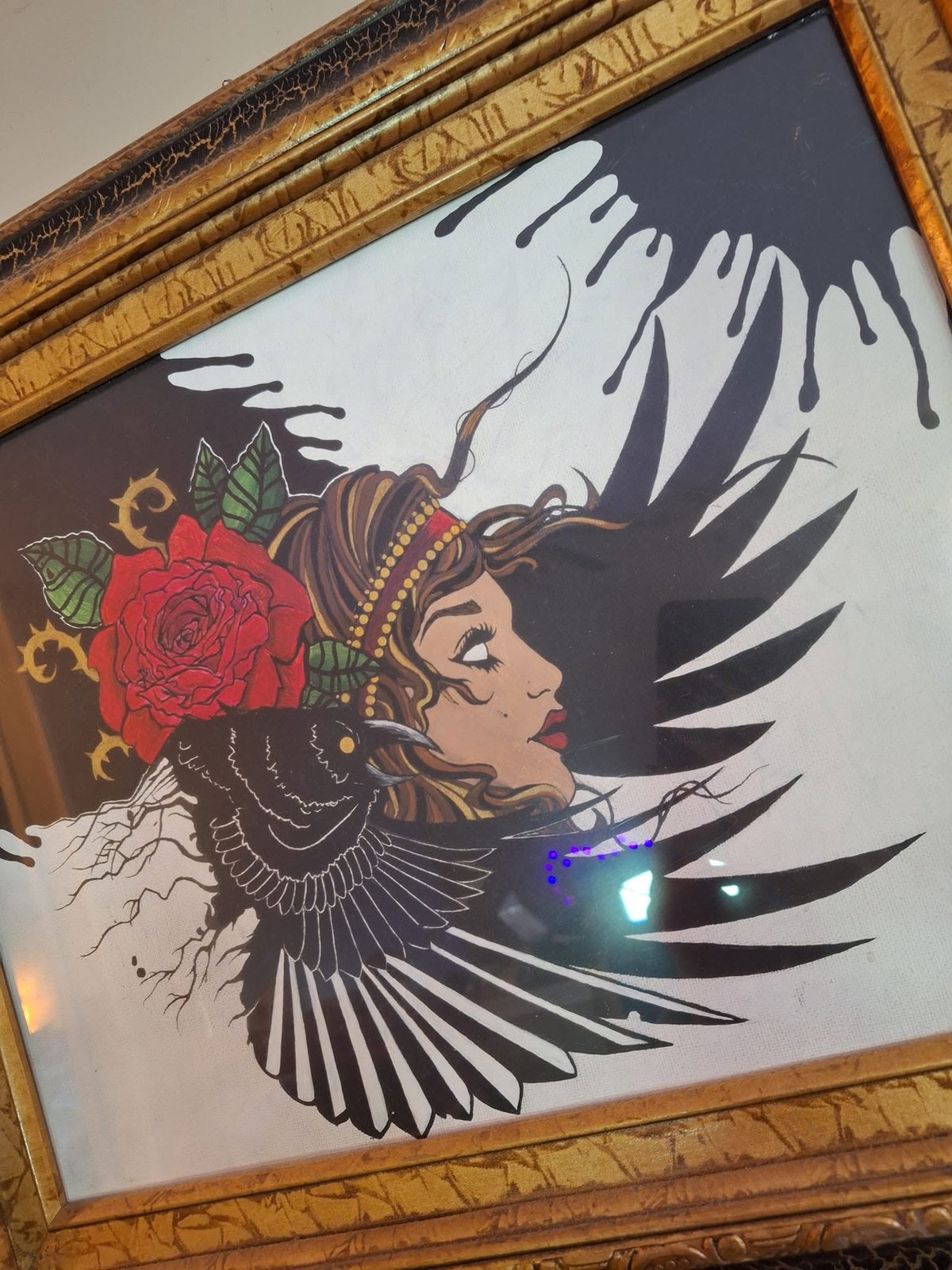 Framed illustration of a woman's profile with a red rose in her hair and a raven spreading its wings across her, black ink dripping from the top of the page